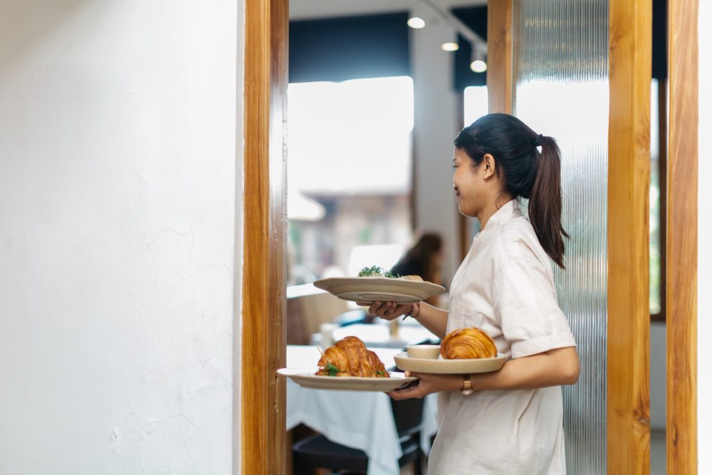 A woman carries 3 plates in her hands