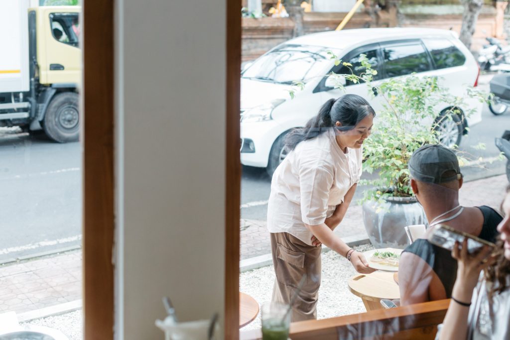 A woman serves a plate of food at Ame Bistro & Coffee