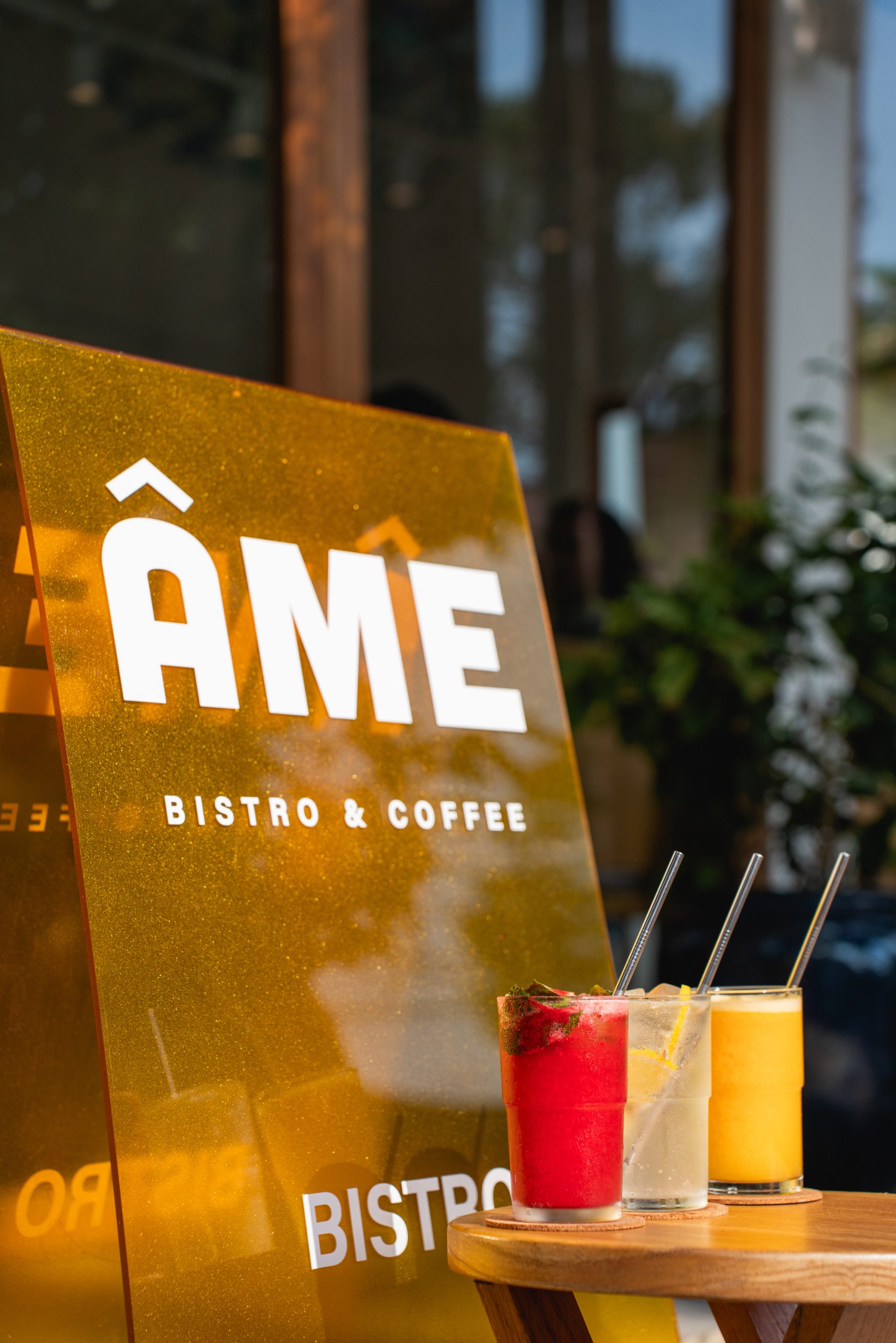 three glass of drink beside ame bistro & coffee sign