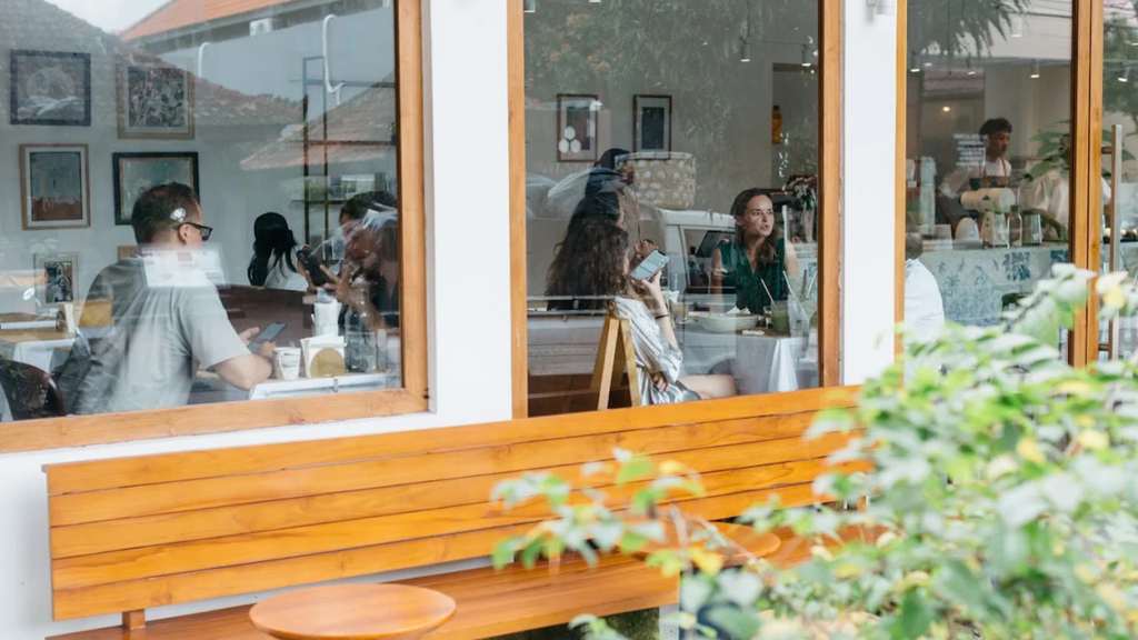 Charming restaurant exterior with large windows, outdoor greenery, and a welcoming dining area.