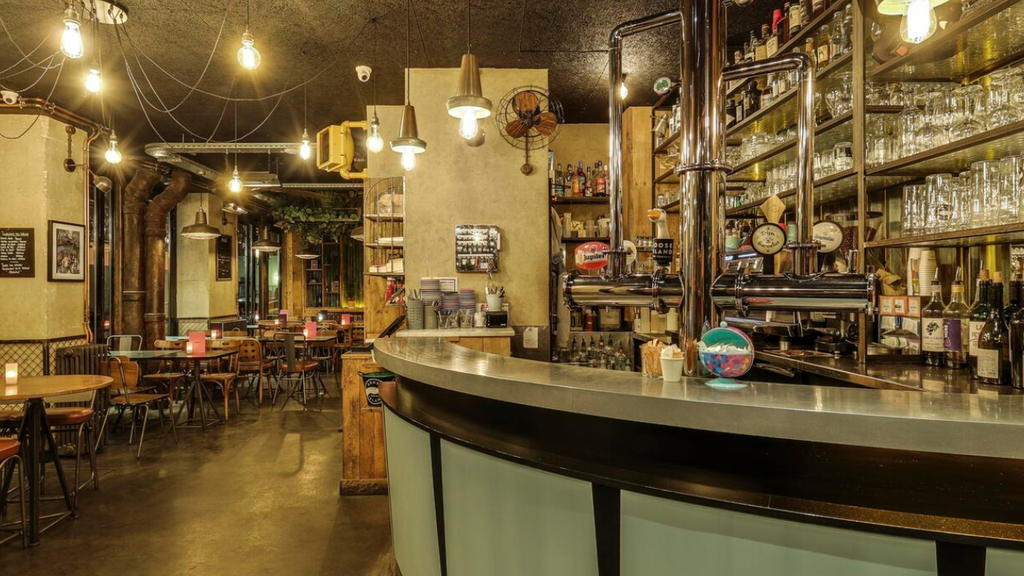 Stylish restaurant dining area with wooden tables, large windows, and lush greenery outside.