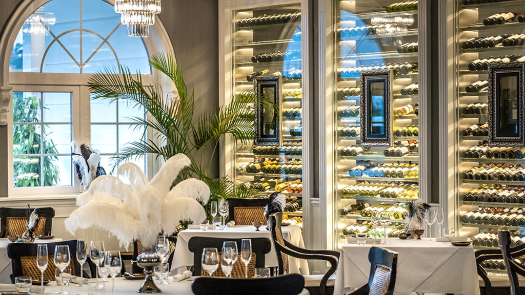 Stylish restaurant dining area with wooden tables, large windows, and lush greenery outside.